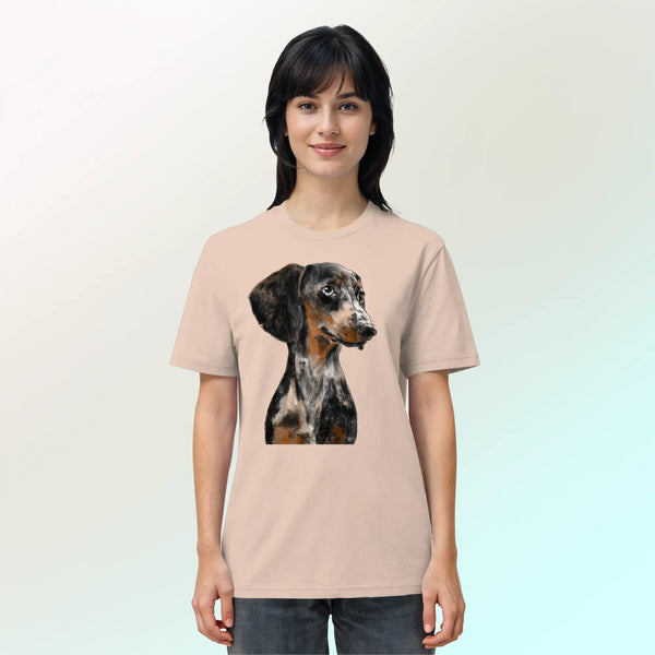 Junge, hübsche Frau trägt ein Bio-T-Shirt in Pfirsichrosa mit handgezeichnetem Dackel-Motiv "Klugi".