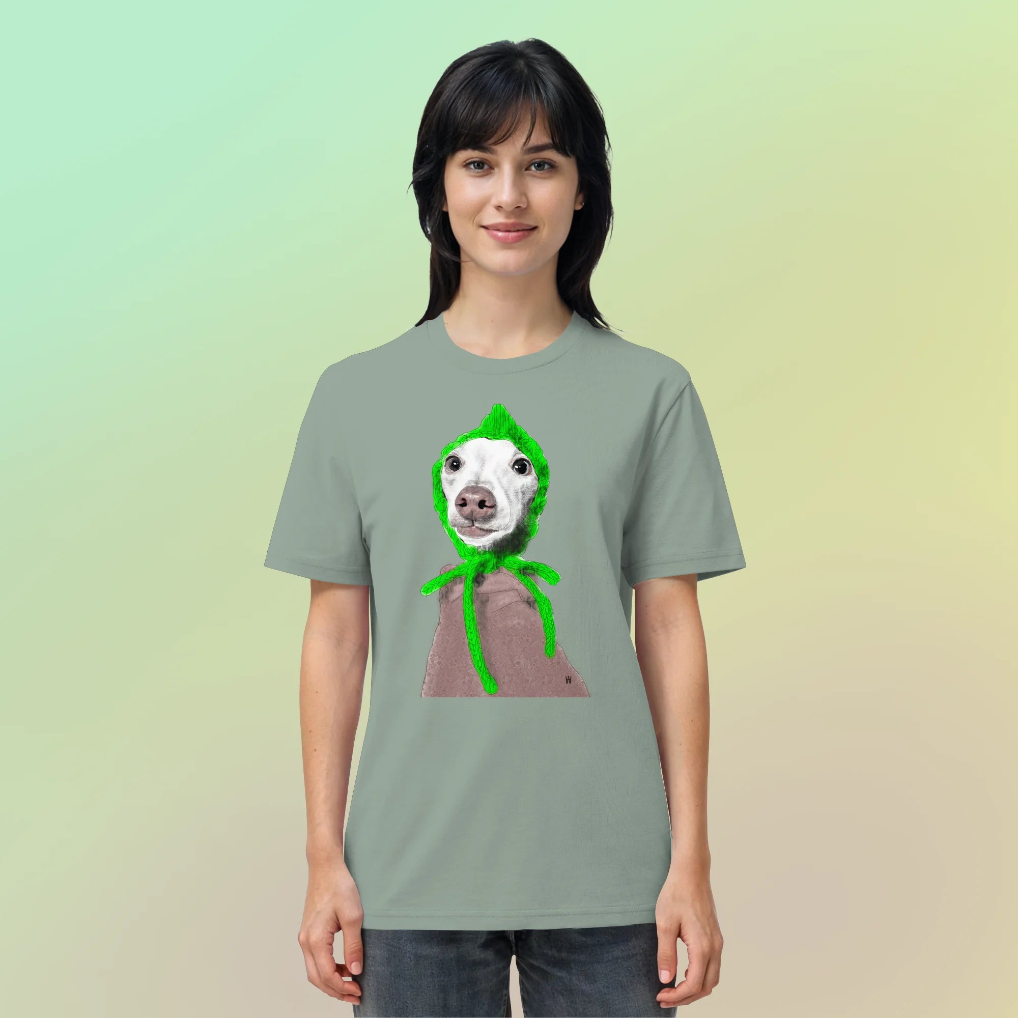 Junge, hübsche Frau trägt handgezeichnete Iggy-Illustration "Geduldig" auf einem salbeigrünen Bio-T-Shirt vor einem zarten Farbverlauf.